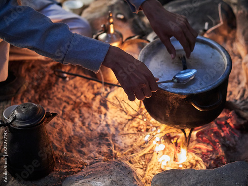Canvas-taulu Bedouin man cooking traditional bedouin meal on fire in a tent