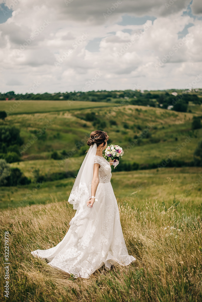 bride in a white dress with a bouquet of flowers in a green field