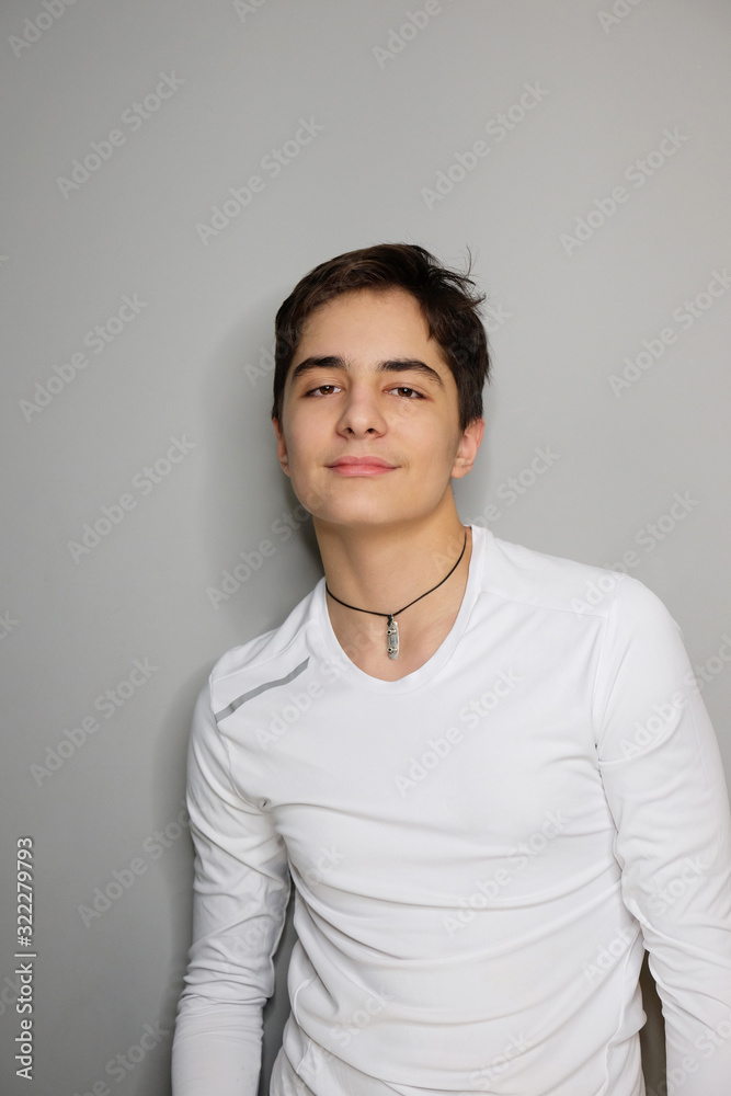 Studio portrait of handsome teenage boy isolated on grey background.