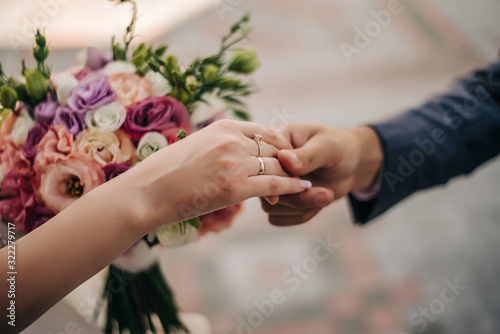 newlyweds hold each other's hands, with a bouquet of flowers in their hands