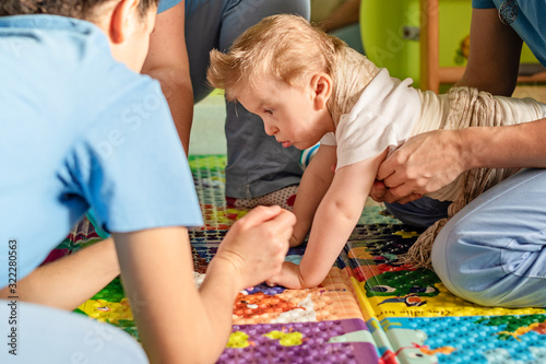 Portrait of a child with cerebral palsy on physiotherapy in a children therapy center. Boy with disability has therapy by doing exercises with physiotherapists in rehabitation centre.