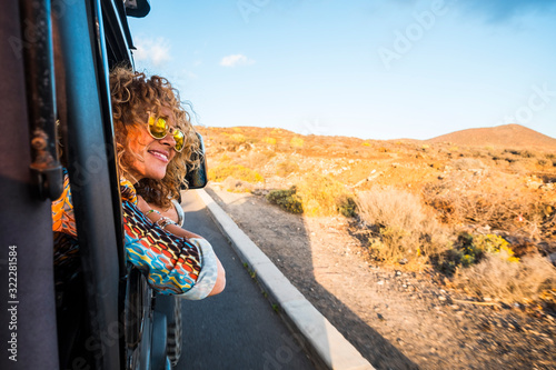 Happy beautiful free modern caucasian woman travel on the road with a car - transport and people enjoying the summer season outside the vehicle - traveler and joyful concept