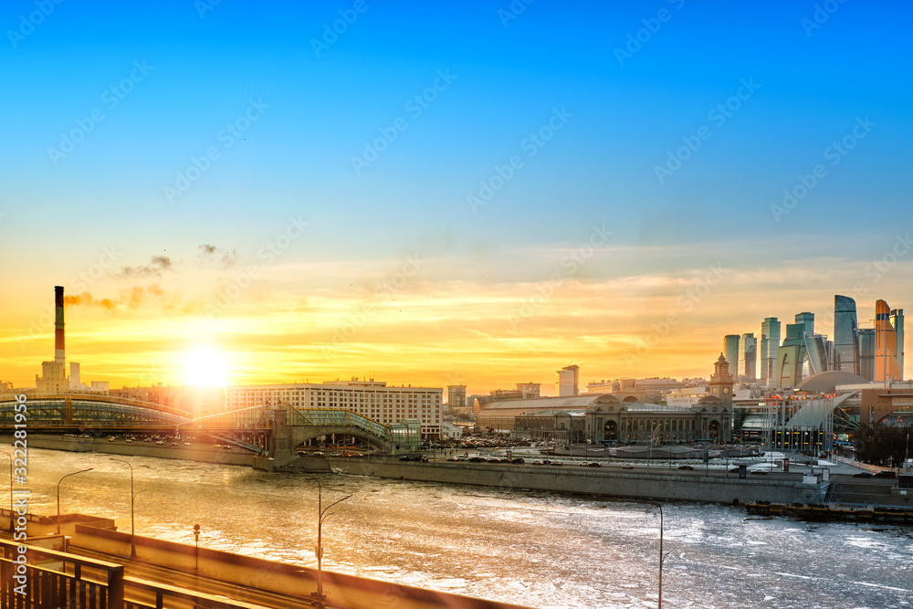 scenic skyline of moscow city russia landmark at winter time against beautiful blue yellow orange red sunset sky background. Wide street view of moscow cityscape with frozen river and skyscrapers