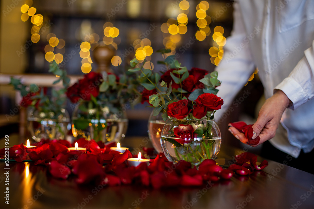 horizontal photo close-up of the process of decorating the festive table with roses and candles