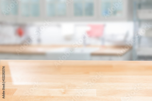 Fototapeta Naklejka Na Ścianę i Meble -  Wooden table top on a blurred background of the kitchen furniture shelves, range hood, and sink. can be used to display or assemble your products