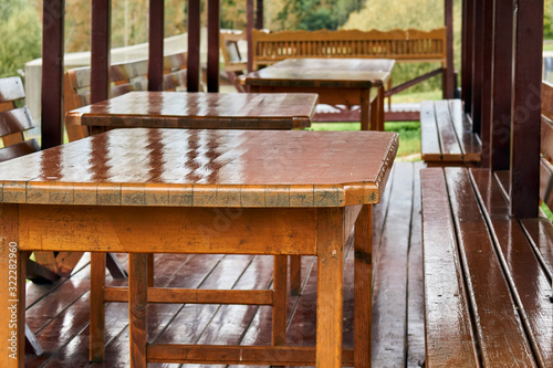 Furniture in a summer cafe. Empty wooden tables and benches stand in a summer cafe