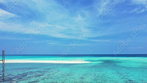 Peaceful seascape with calm clear water of turquoise lagoon, coral reef patterns under water and blue sky with white clouds in Maldives photo