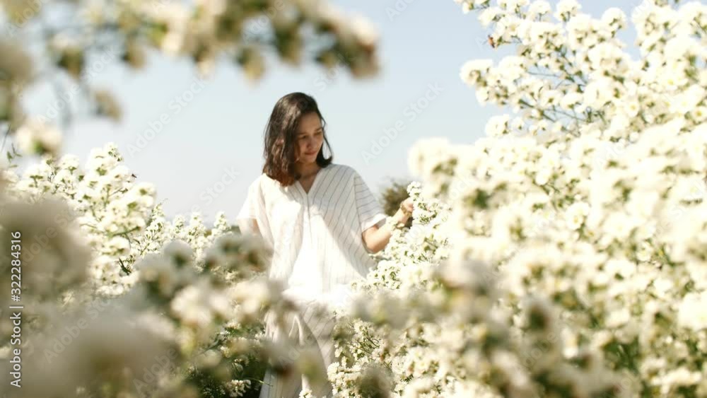 Young woman sitting in a white flower garden. Young woman sitting in a white flower garden.