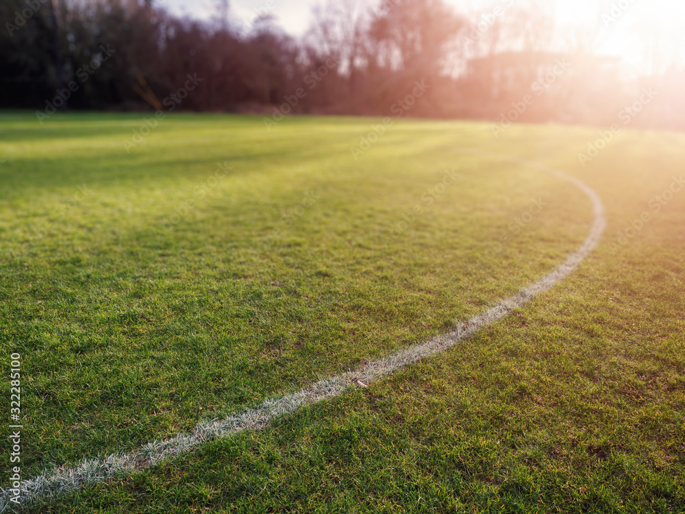 Obraz premium Line on a grass for outdoors sports like soccer, rugby hurling at sun set, Warm sun flare, Concept active sport facility.