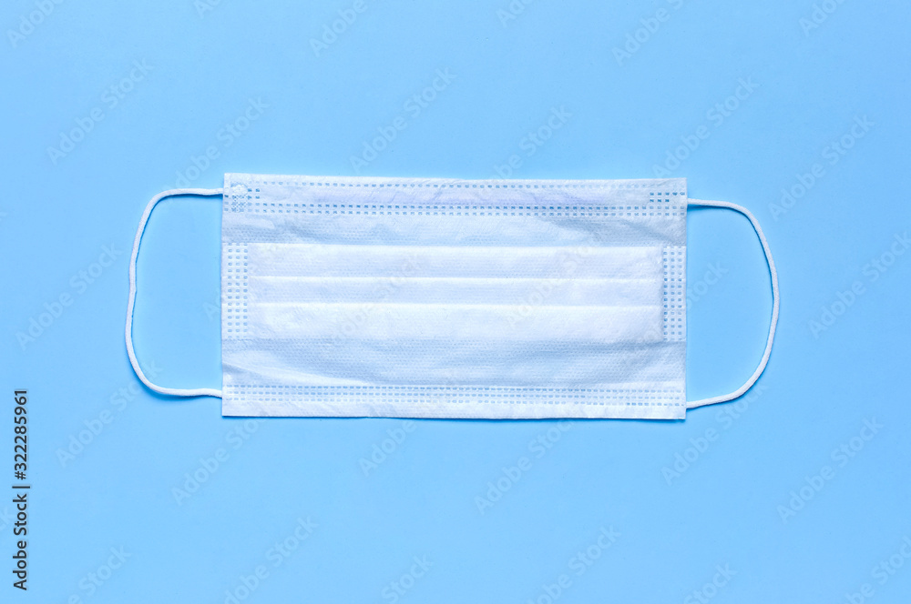 Medical mask on blue background flat lay top view with copy space. Protection against virus, coronavirus, flu, colds, diseases. Traditional medical tool, concept of health. Medical background Medical mask on blue background flat lay top view with copy space. Protection against virus, coronavirus, flu, colds, diseases. Traditional medical tool, concept of health. Medical background