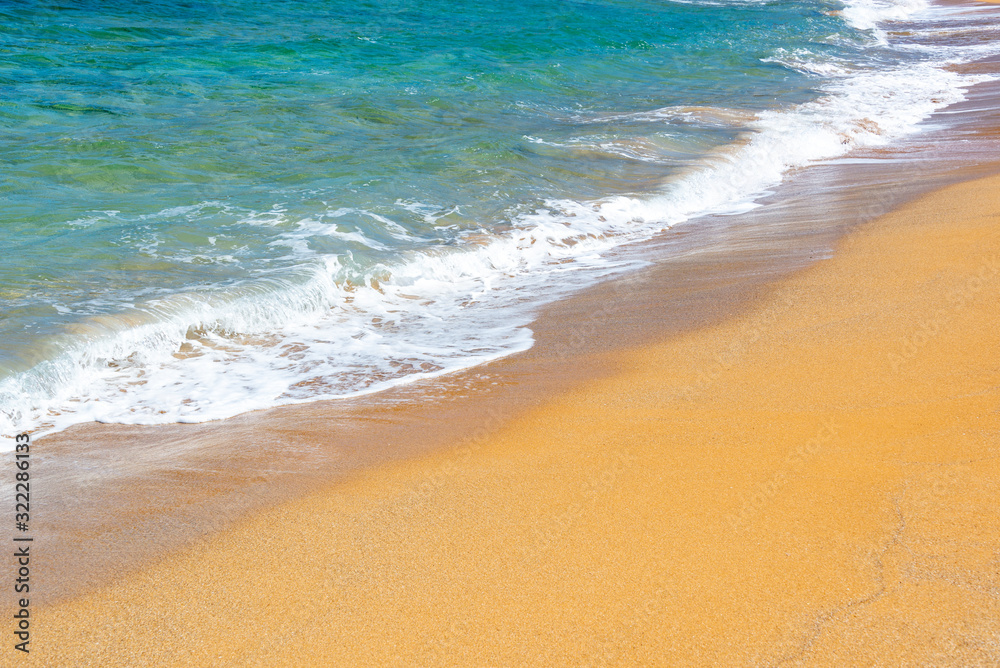 Waves on a beach with orange sand and blue water