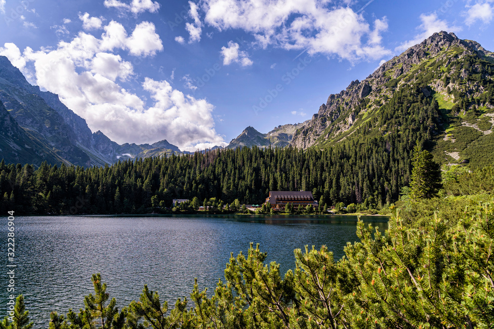 Scenic view of beautiful mountain landscape with mountain cabin/hut next to a lake. Popradske Pleso Town in High Tatras National Park, Slovakia.