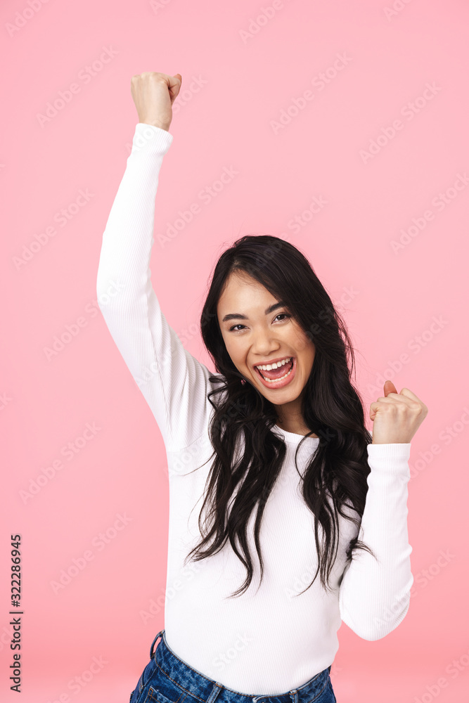 Image of young brunette asian woman smiling and celebrating triumph Image of young brunette asian woman smiling and celebrating triumph
