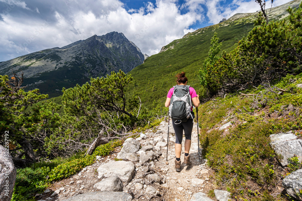 Young woman on a mountain terrain trail. Hiking in High Tatras National Park, Slovakia.
