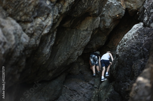 Принти на полотні Two young boys climbing rocks by the beach at Coral Beach near Shute Harbour in