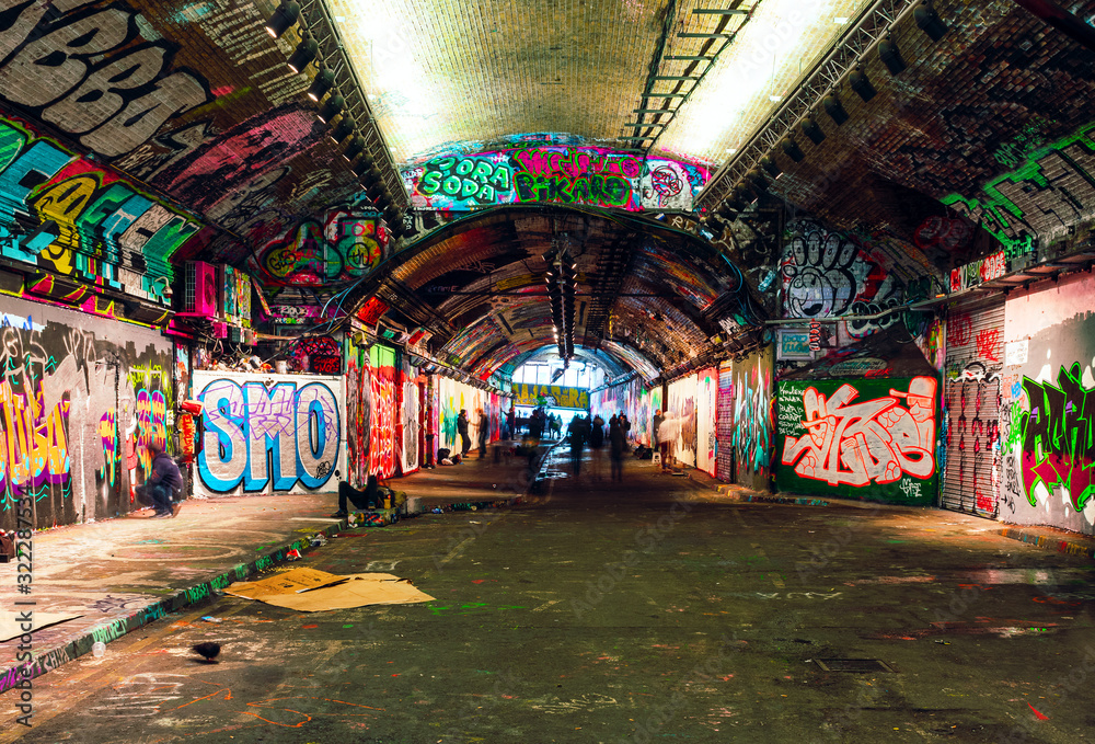 Fototapeta London, UK/Europe; 21/12/2019: Leake Street, underground tunnel with graffiti covered walls in London. Scene with pedestrians and graffiti artists.