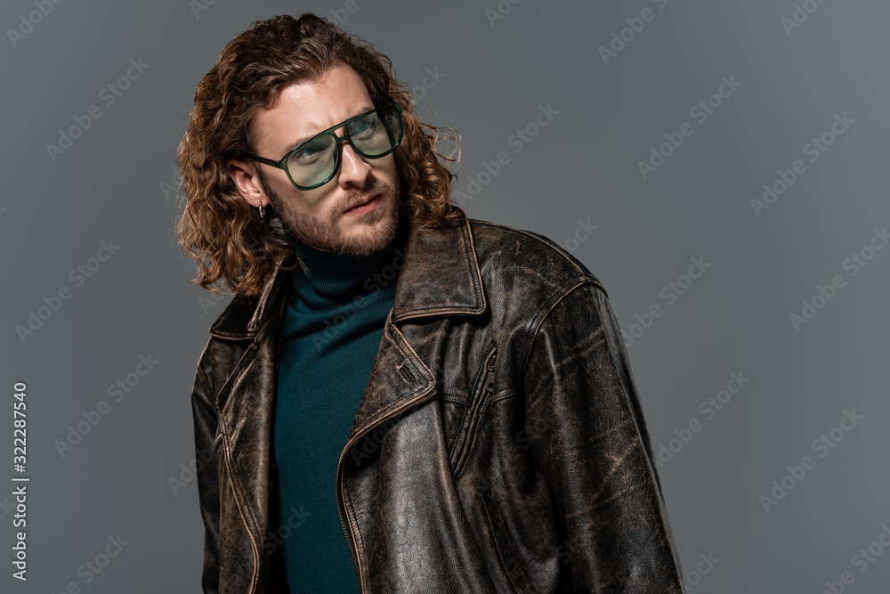 handsome man in leather jacket looking away isolated on grey