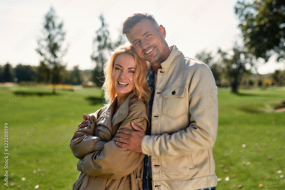 In love. Portrait of romantic couple hugging and smiling while standing in the middle of the beautiful park