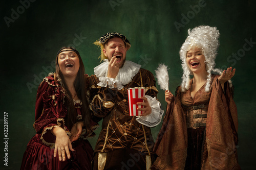 Funny cinema. Portrait of medieval young people in vintage clothing on dark background. Models as a duke and duchess, princess, royal persons. Concept of comparison of eras, modern, fashion.