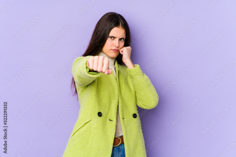 Young caucasian woman isolated on purple background throwing a punch, anger, fighting due to an argument, boxing. Young caucasian woman isolated on purple background throwing a punch, anger, fighting due to an argument, boxing.