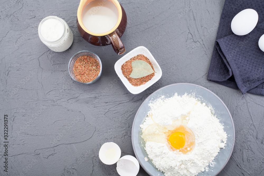 The ingredients for making the dough, including eggs, milk, flour and pepper and spices, are next to a rolling pin and a kitchen towel. The concept of preparation of the dough or baking recipes. The ingredients for making the dough, including eggs, milk, flour and pepper and spices, are next to a rolling pin and a kitchen towel. The concept of preparation of the dough or baking recipes.