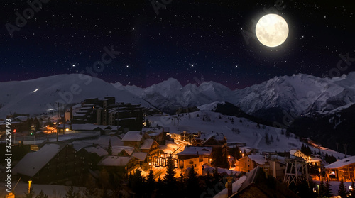 Night landscape and ski resort in French Alps, Alpes d'Huez, France, Huge Moon and Starry Sky