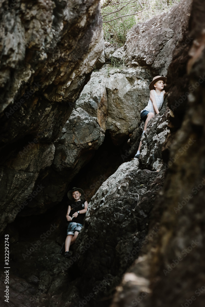 Moody image of young boys exploring cave by the beach at Coral Beach near Shute Harbour in the Whitsundays, Queensland Australia