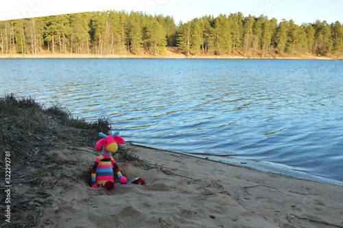 Amigurumi dolls are photographed outdoors by the lake.