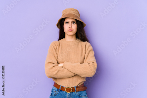 Young caucasian woman isolated on purple background blows cheeks, has tired expression. Facial expression concept.