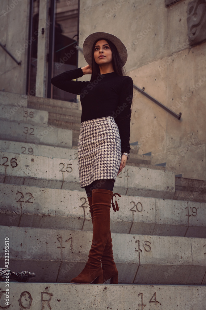 stylish girl in a hat with long hair posing on the steps of the building