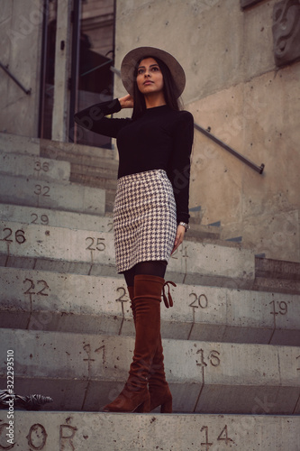 Obraz na płótnie stylish girl in a hat with long hair posing on the steps of the building w salonie
