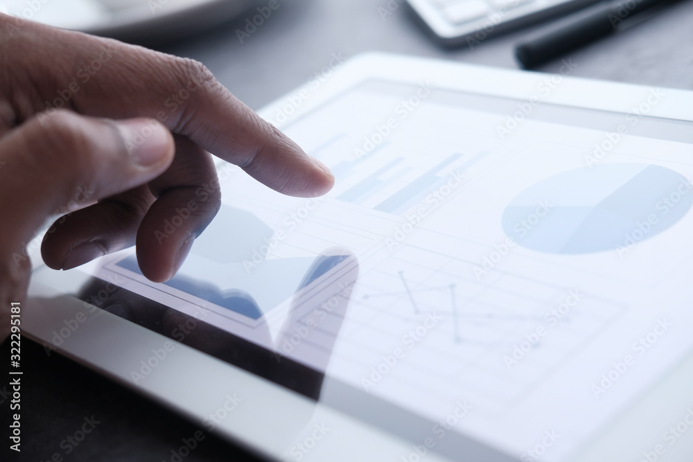 Fototapeta premium Businessman hand analyzing chart on digital tablet, closeup