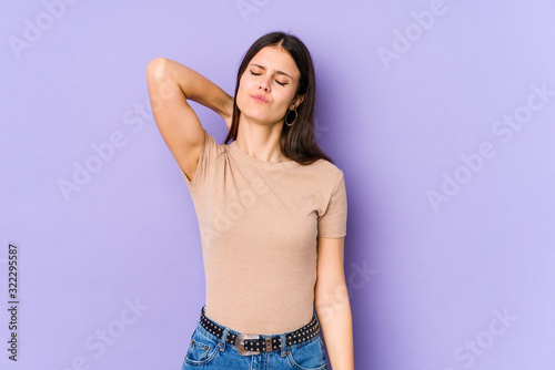 Young caucasian woman isolated on purple background having a neck pain due to stress  massaging and touching it with hand.