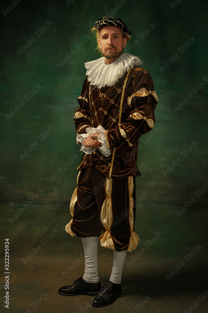 Fotka „Posing thoughtful. Portrait of medieval young man in vintage  clothing standing on dark background. Male model as a duke, prince, royal  person. Concept of comparison of eras, modern, fashion.“ ze služby