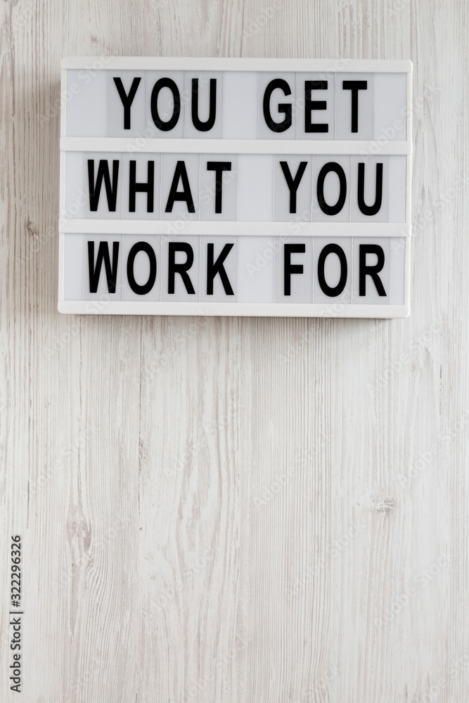 'You get what you work for' words on a lightbox on a white wooden surface, overhead view. Top view, from above, flat lay. Space for text. 'You get what you work for' words on a lightbox on a white wooden surface, overhead view. Top view, from above, flat lay. Space for text.