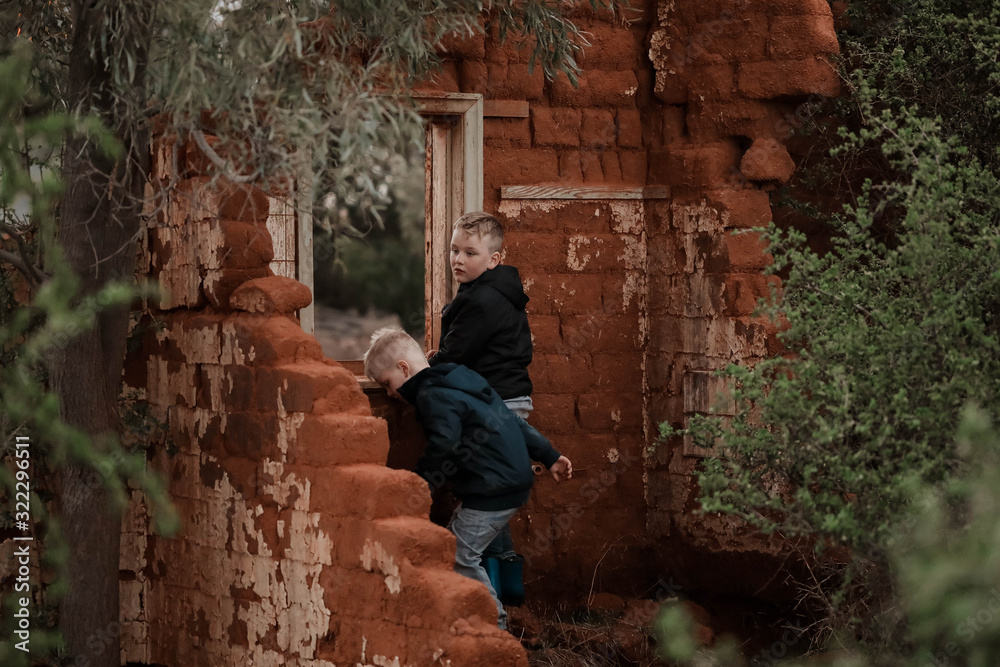 Two boys exploring ruins of fallen down mud brick house