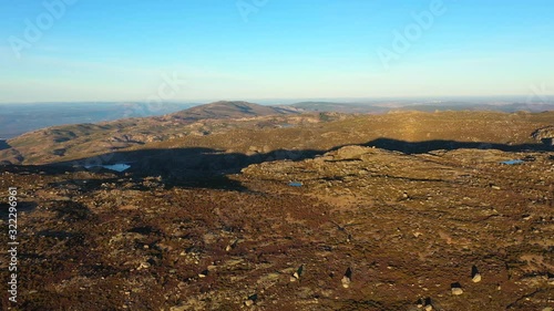 Aerial, pan, drone shot, over rocky nature, towards the lake Lagoa Comprida and Maques da silva dam, at sunset, Serra da Estrela, Guarda, Portugal
