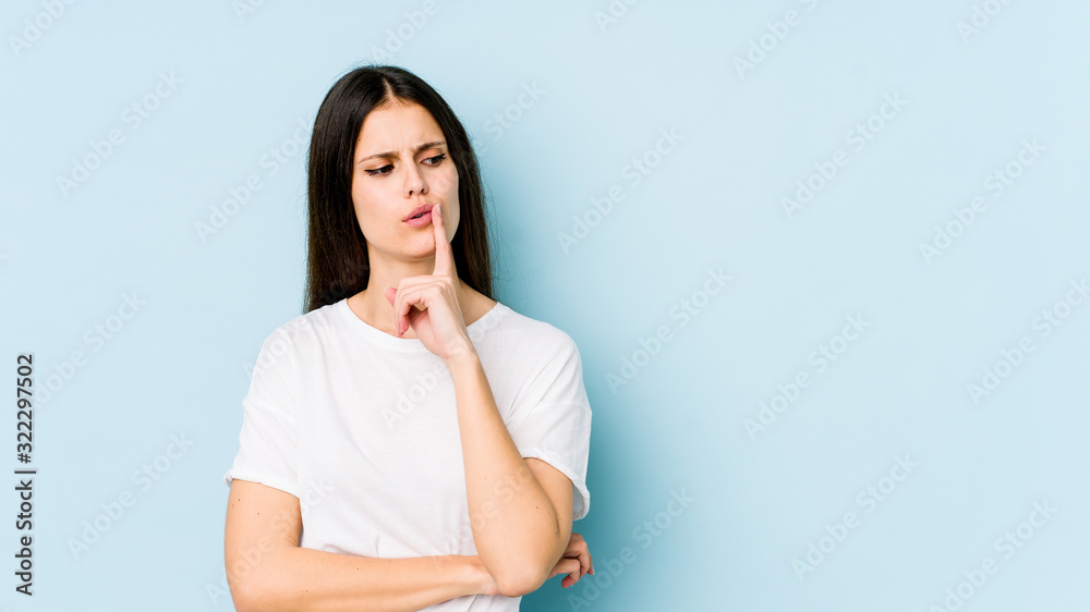 Young caucasian woman isolated on blue background looking sideways with doubtful and skeptical expression. Young caucasian woman isolated on blue background looking sideways with doubtful and skeptical expression.