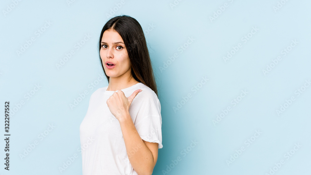 Young caucasian woman isolated on blue background points with thumb finger away, laughing and carefree. Young caucasian woman isolated on blue background points with thumb finger away, laughing and carefree.