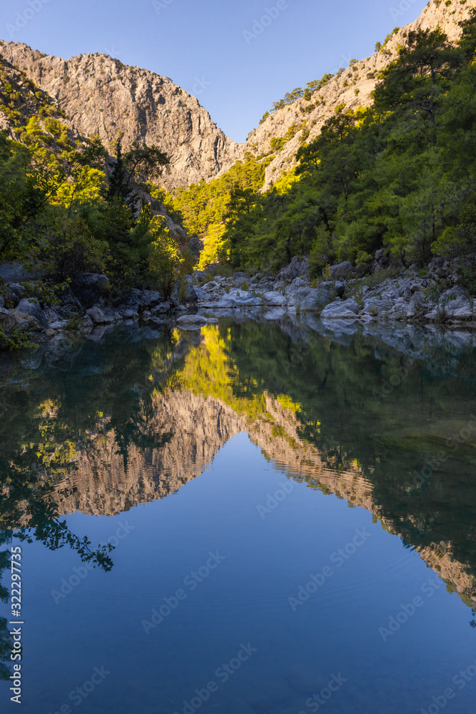 Hdr vertical photo of beautiful mountain landscape with peaceful calm surface of river in foreground.