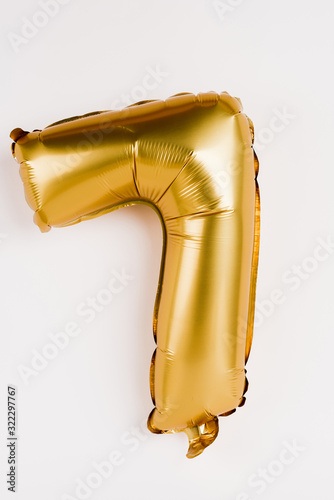 Golden balloon in shape of seven number on grey background