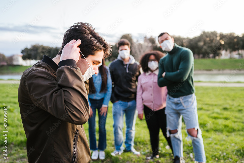 Group of teenagers friends at park wearing medical masks to protect from infections and diseases - Conceptual Coronavirus virus quarantine - Copy space - Multiracial people having fun together Group of teenagers friends at park wearing medical masks to protect from infections and diseases - Conceptual Coronavirus virus quarantine - Copy space - Multiracial people having fun together