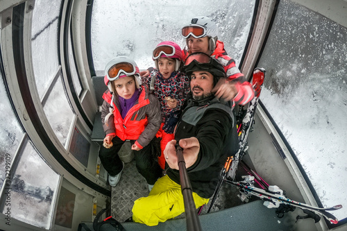 Family riding cabin cable car on winter vacation skiing.
