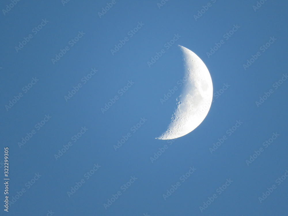 Waxing quarter moon at dusk twilight with craters mountains and maria visible Waxing quarter moon at dusk twilight with craters mountains and maria visible