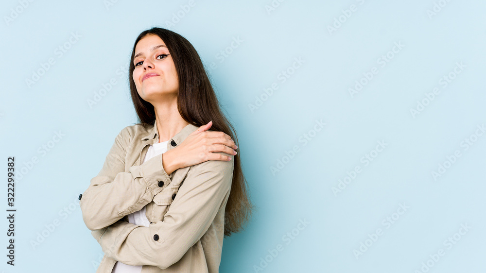 Young caucasian woman isolated on blue background hugs, smiling carefree and happy. Young caucasian woman isolated on blue background hugs, smiling carefree and happy.