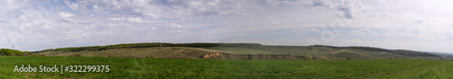 Panoramic view. Beautiful natural landscape. Green hills, meadows and forest on a blue sky background