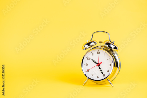 Silver alarm clock on yellow background