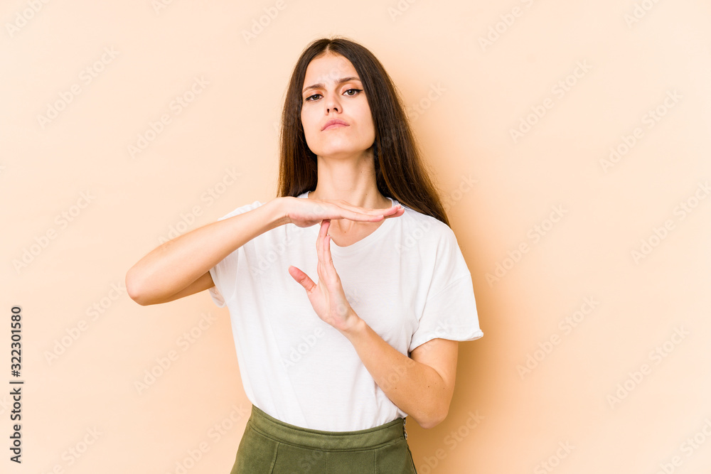 Young caucasian woman isolated on beige background showing a timeout gesture. Young caucasian woman isolated on beige background showing a timeout gesture.