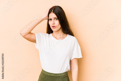 Young caucasian woman isolated on beige background being shocked, she has remembered important meeting.