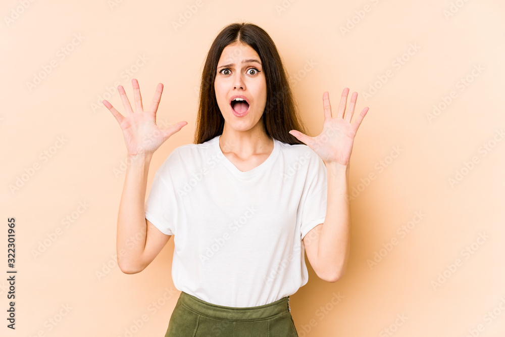 Young caucasian woman isolated on beige background screaming to the sky, looking up, frustrated. Young caucasian woman isolated on beige background screaming to the sky, looking up, frustrated.